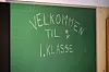 Grøn tavle med teksten «Velkommen til 1. klasse» og eit lite hjarte.