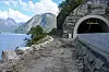 Nyleg avdekka veg langs ein fjord, med steinmur og tunnelopning i bratt fjell.