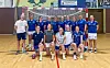 Handballspelarar og trenarar i blå drakter poserer samla i ein idrettshall.